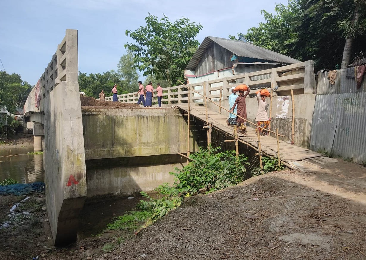 মানুষজন হেঁটে পার হলেও বিকল্প সড়ক না থাকায় ভারি পণ্যও নিতে হচ্ছে মাথায় করে। ছবি: সমাজকাল