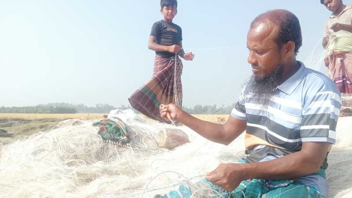 মন দিয়ে জাল মেরামত করছেন